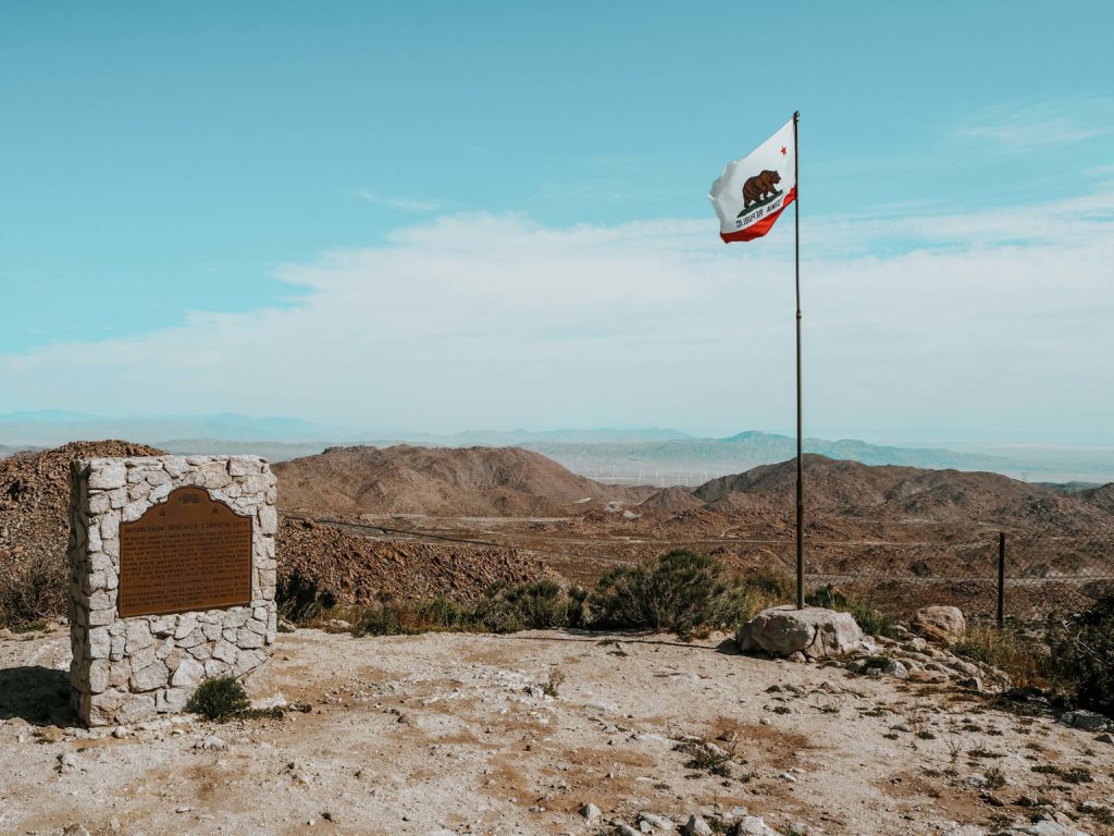 Picture shows the California Flag and the view across the desert from the Desert View Tower in Jacumba which is a stop on this Southwest Road Trip